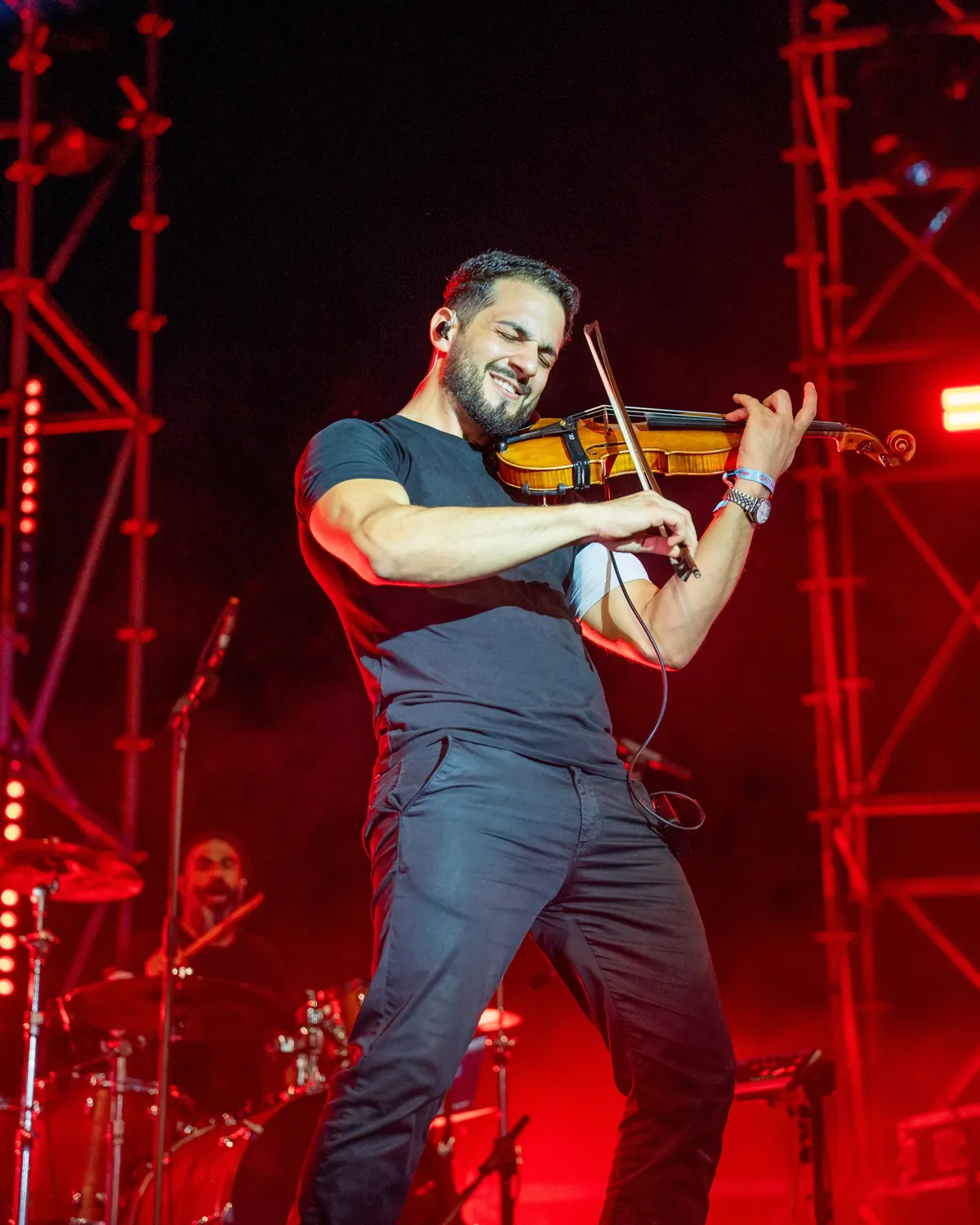 Marios playing violin on stage in red light