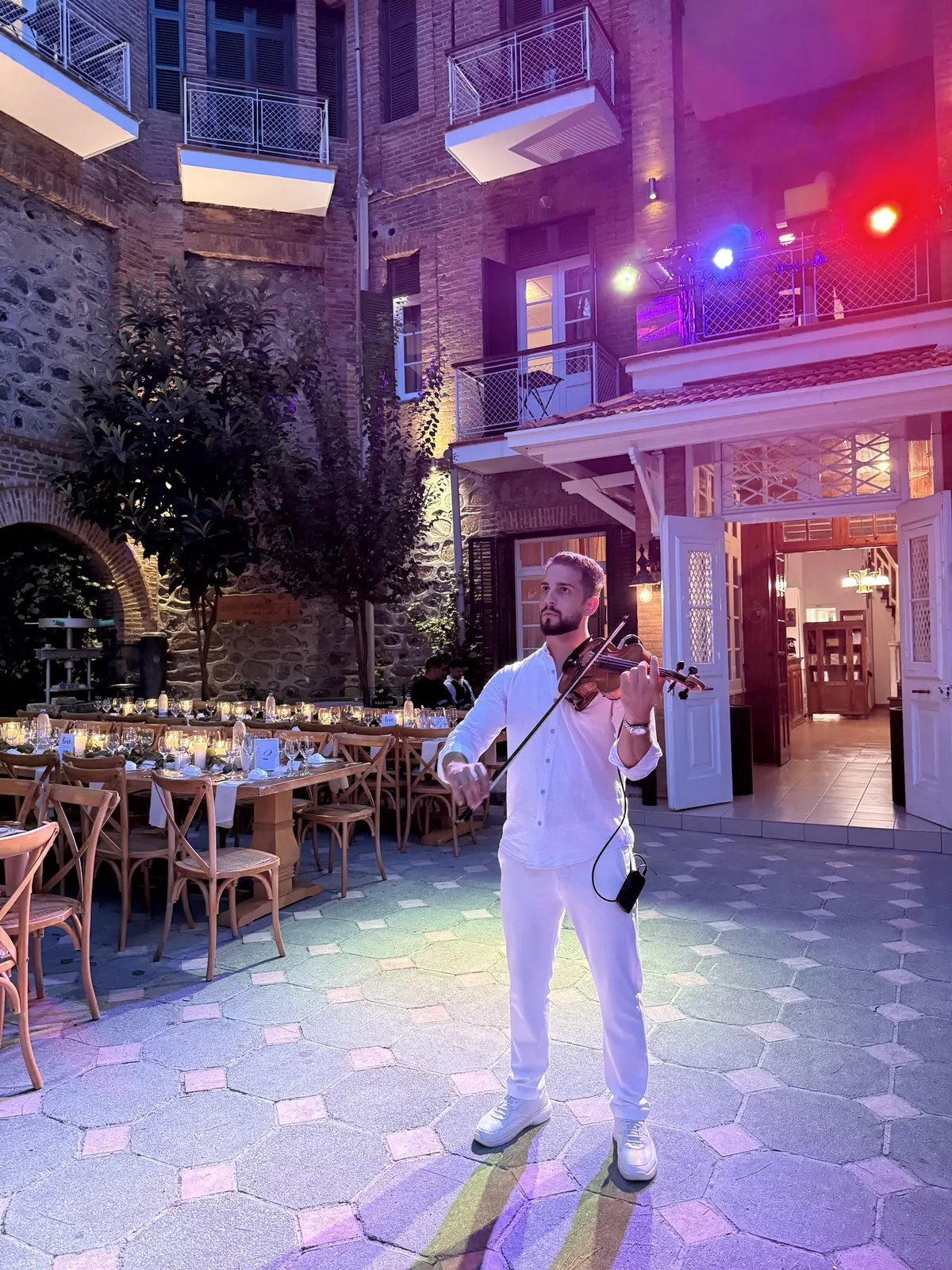 Marios playing violin in a lit courtyard
