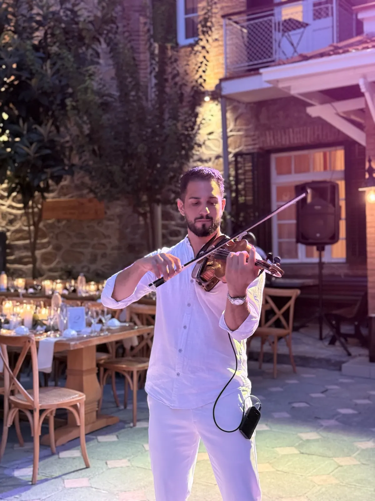 Marios playing violin, close-up, in an evening courtyard