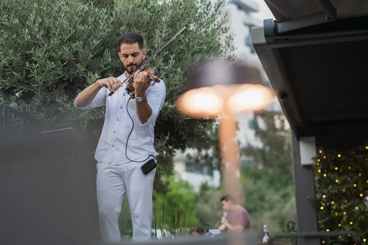 Marios playing violin outdoors among olive trees