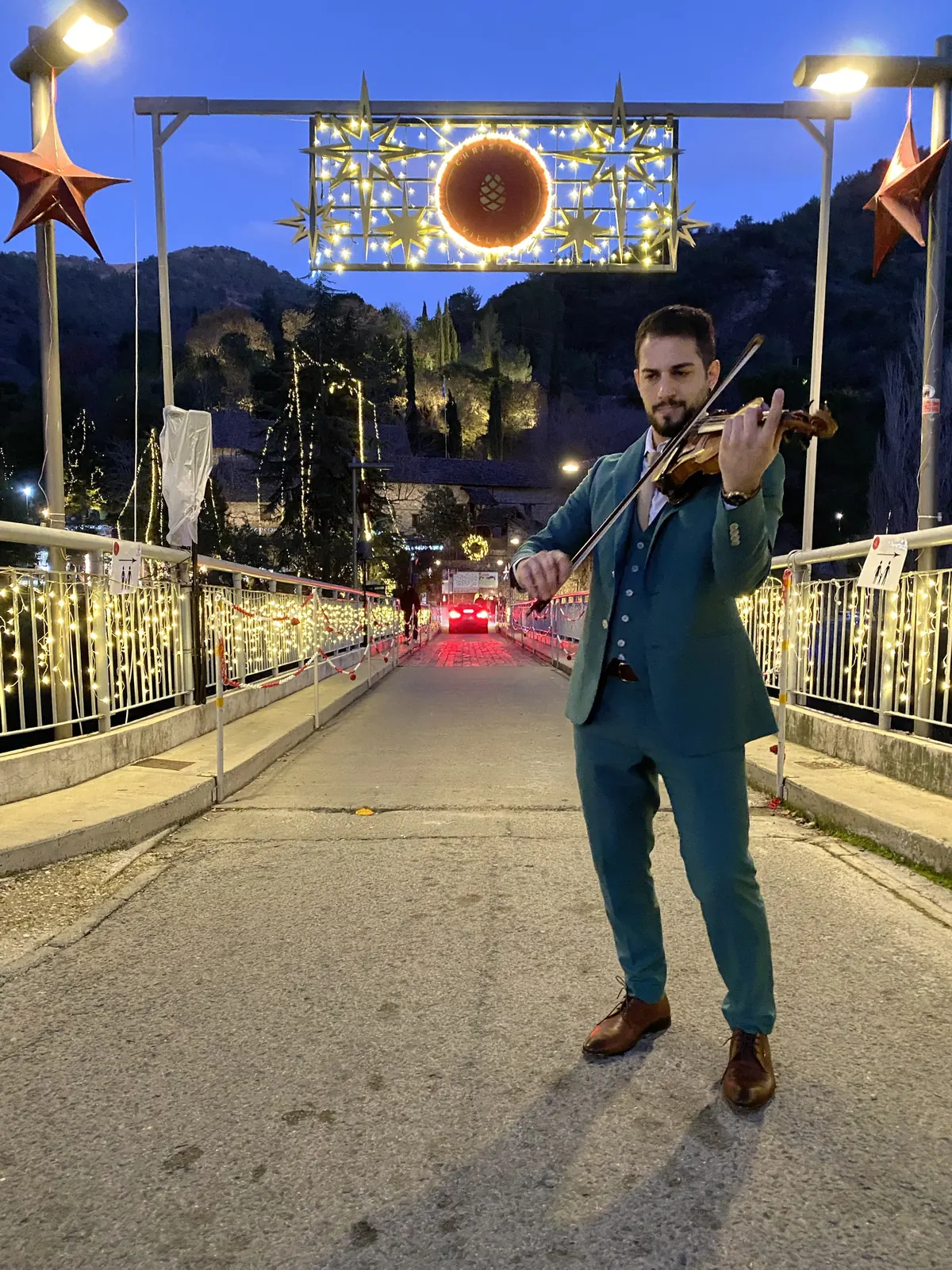 Marios in a green suit playing violin on a decorated bridge