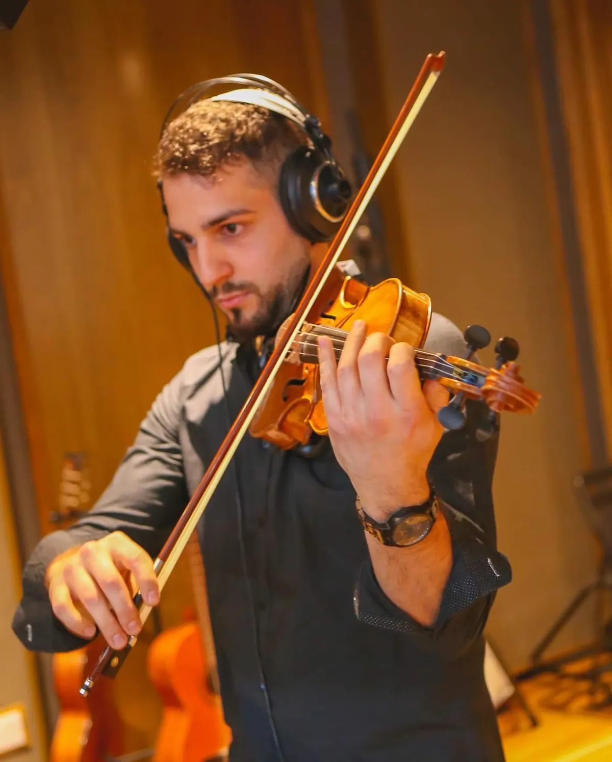 Marios playing violin in a studio with headphones
